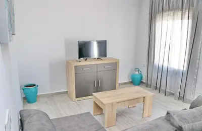 a living room with a tv on a stand with a table at Chalet Lobita in Conil de la Frontera