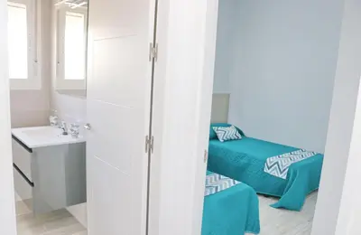 a small bathroom with two beds and a sink at Chalet Lobita in Conil de la Frontera