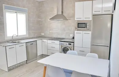 a kitchen with white cabinets and a white table at Chalet Lobita in Conil de la Frontera