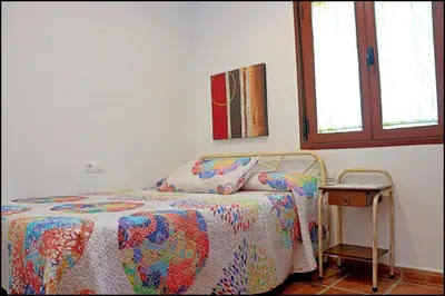 a bedroom with a bed with a quilt and a table at Chalet Puente de Tabla in Conil de la Frontera