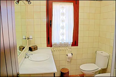 a bathroom with a sink and a toilet and a window at Chalet Puente de Tabla in Conil de la Frontera