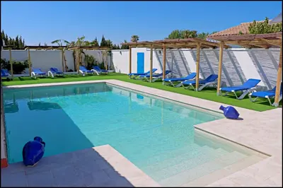 a large swimming pool with blue chairs and chairs at Bungalow La Roa IV in Conil de la Frontera