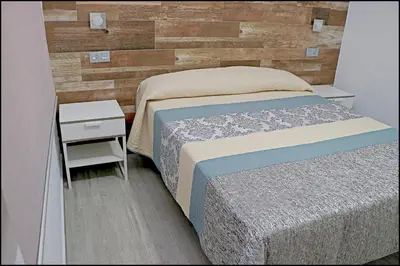 a bedroom with a bed and a wooden wall at Bungalow La Roa IV in Conil de la Frontera