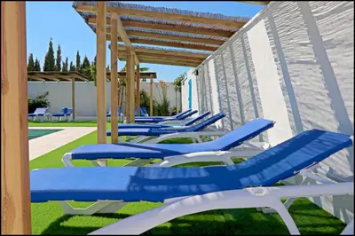 a row of blue and white lounge chairs on the grass at Bungalow La Roa IV in Conil de la Frontera