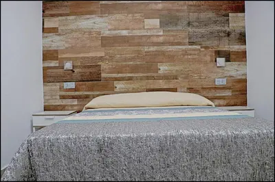 a bed with a wooden wall behind it at Bungalow La Roa IV in Conil de la Frontera