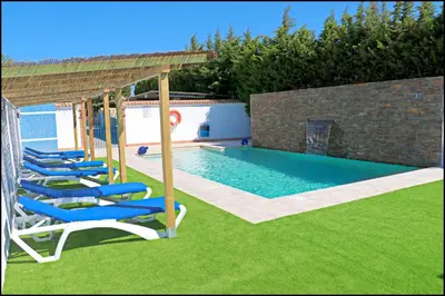 a pool with lounge chairs and a gazebo at Bungalow La Roa IV in Conil de la Frontera