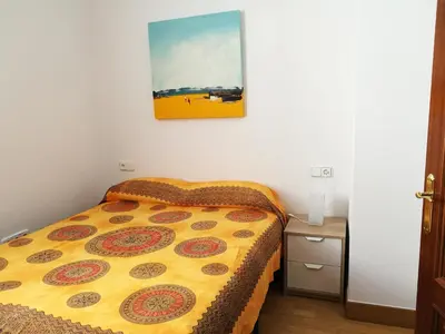 a bed in a small room with a picture on the wall at Apartamento Aldama en el centro de Sanlúcar de Barrameda in Sanlúcar de Barrameda