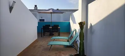 a patio with a table and an umbrella and chairs at Apartamento Aldama en el centro de Sanlúcar de Barrameda in Sanlúcar de Barrameda