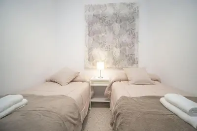 two beds in a room with a lamp on a table at Apartamento ateneo in Sanlúcar de Barrameda