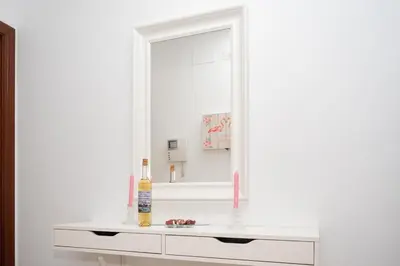 a white bathroom with a mirror and a sink at Apartamento ateneo in Sanlúcar de Barrameda