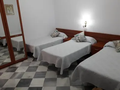 a room with three beds and a mirror at Hostal Centro Sol in Cádiz