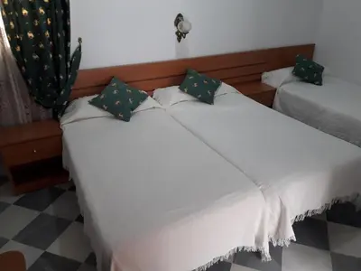 two beds in a room with white sheets at Hostal Centro Sol in Cádiz