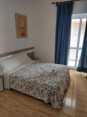 a bedroom with a bed with a comforter on it at Hostal Fantoni in Cádiz