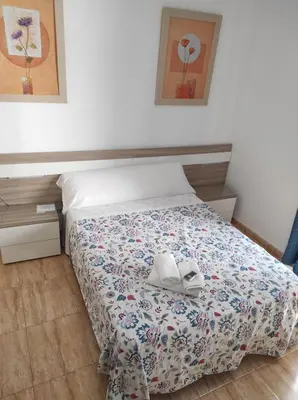 a bedroom with a bed with two books on it at Hostal Fantoni in Cádiz