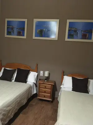 a bedroom with two beds and a night stand with two lamps at Hostal Fantoni in Cádiz