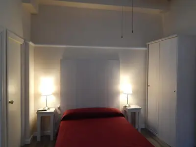 a bedroom with a red bed and two lamps on tables at Hospederia Marqués in Cádiz
