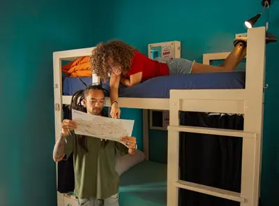 a man holding a piece of paper in front of two bunk beds at Casa Caracol in Cádiz