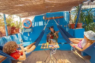 two women sitting in hammocks in a blue room at Casa Caracol in Cádiz