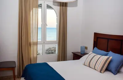 a bedroom with a bed and a window with the ocean at Apartamento Barrosaplaya1 in Chiclana de la Frontera