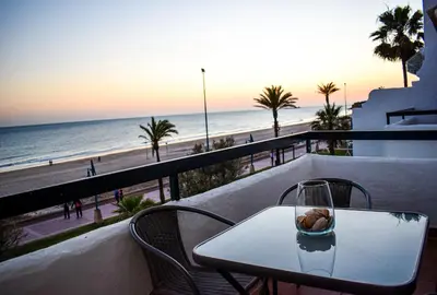 a table and chairs on a balcony with a view of the beach at Apartamento Barrosaplaya1 in Chiclana de la Frontera