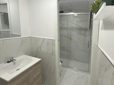 a white bathroom with a shower and a sink at Gran Teatro Falla in Cádiz