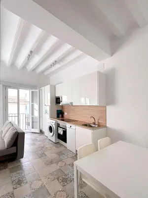 a kitchen with white cabinets and a table in a room at Gran Teatro Falla in Cádiz