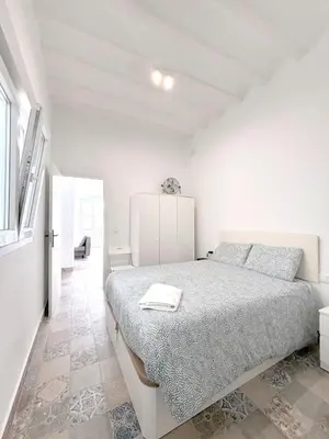 a white bedroom with a bed and a refrigerator at Gran Teatro Falla in Cádiz