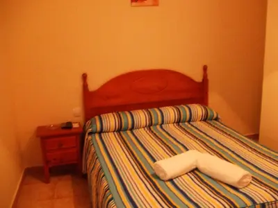 a bedroom with a bed with a wooden head board at Apartamentos Las Parcelas in Conil de la Frontera
