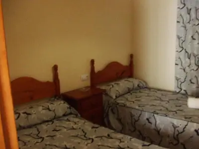 a bedroom with two beds and a night stand at Apartamentos Las Parcelas in Conil de la Frontera