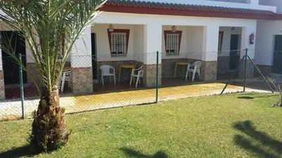a palm tree in front of a house with a fence at Apartamentos Las Parcelas in Conil de la Frontera