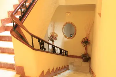 a hallway with a staircase with a mirror and flowers at Hotel El Coloso in Jerez de la Frontera