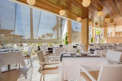 a restaurant with white tables and white chairs at Hipotels Playa La Barrosa - Adults Only in Chiclana de la Frontera