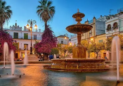 a fountain in the middle of a square with buildings at Playa de la Calzada in Sanlúcar de Barrameda