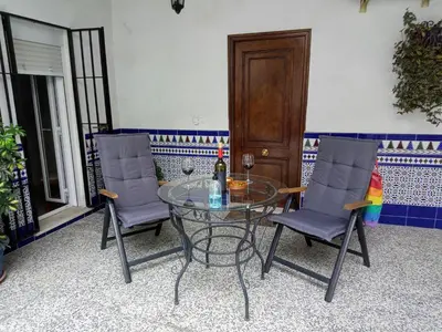 a glass table with two chairs and a bottle of wine at Casa Valientes A - Parking privado gratis & patio interior in Jerez de la Frontera