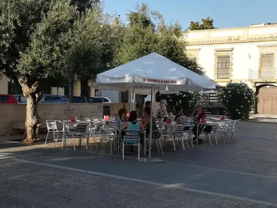a group of people sitting at tables under an umbrella at Casa Valientes A - Parking privado gratis & patio interior in Jerez de la Frontera