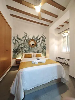 a bedroom with a large bed with a painting on the wall at Apartamento del Mercado Little Apartments in Cádiz
