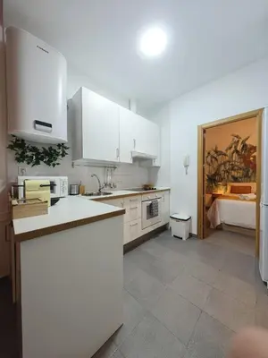 a kitchen with white cabinets and a bed in a room at Apartamento del Mercado Little Apartments in Cádiz