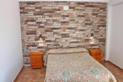 a bedroom with a bed and a brick wall at Chalet Pradillo in Conil de la Frontera