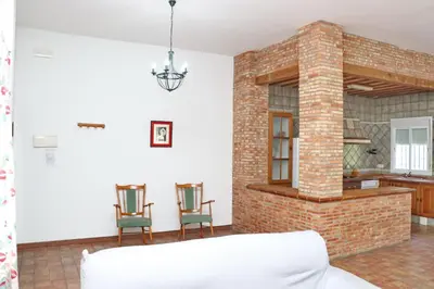 a living room with two chairs and a brick fireplace at Chalet Pradillo in Conil de la Frontera