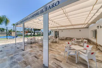a pavilion with tables and chairs and a pool at Hostal del Faro in Conil de la Frontera