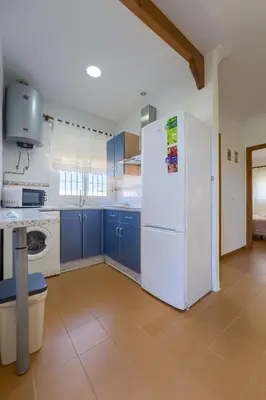 a kitchen with blue cabinets and a white refrigerator at Hostal del Faro in Conil de la Frontera