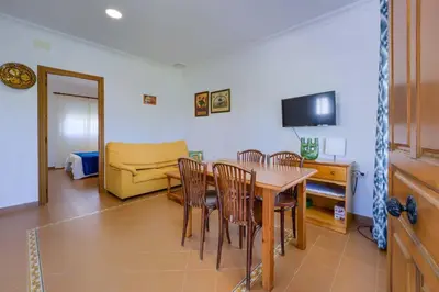 a dining room with a table and chairs and a couch at Hostal del Faro in Conil de la Frontera