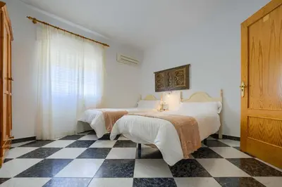 a bedroom with two beds and a checkered floor at Hostal del Faro in Conil de la Frontera