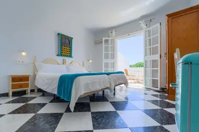 a bedroom with a bed and a checkered floor at Hostal del Faro in Conil de la Frontera