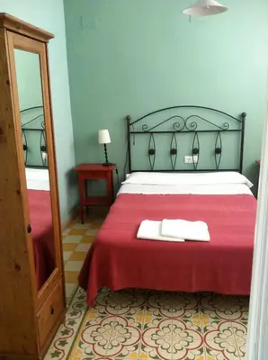 a bedroom with a bed with a red blanket and a mirror at Pensión España in Cádiz