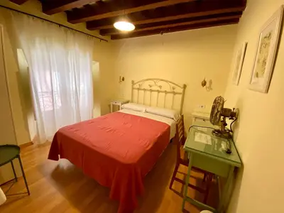 a bedroom with a bed with a red blanket and a table at Pensión España in Cádiz