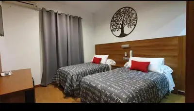 a hotel room with two beds and a clock on the wall at Hostal San Francisco in Cádiz