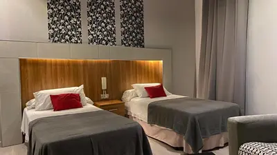 a hotel room with two beds and a chair at Hostal San Francisco in Cádiz