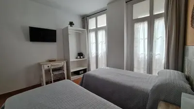 a hotel room with two beds and a window at Hostal Canalejas in Cádiz