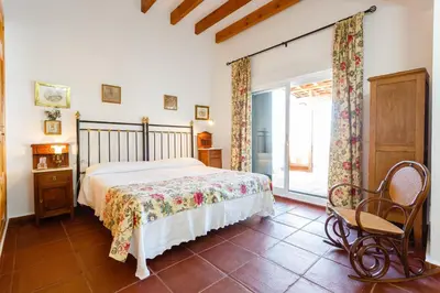a bedroom with a bed and a chair and a window at Bonito Chalet Con Vistas in Sanlúcar de Barrameda